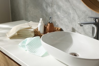 Photo of Clean waffle towels and cosmetic products on counter in bathroom