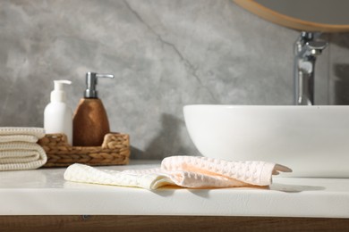 Photo of Clean waffle towels and cosmetic products on counter in bathroom, closeup
