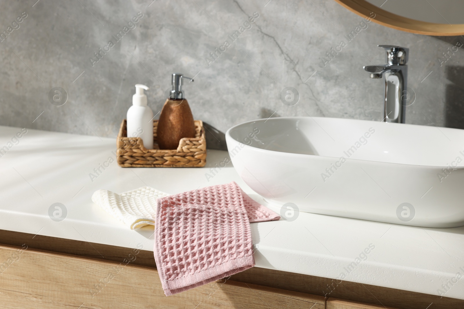 Photo of Clean waffle towels and cosmetic products on counter in bathroom