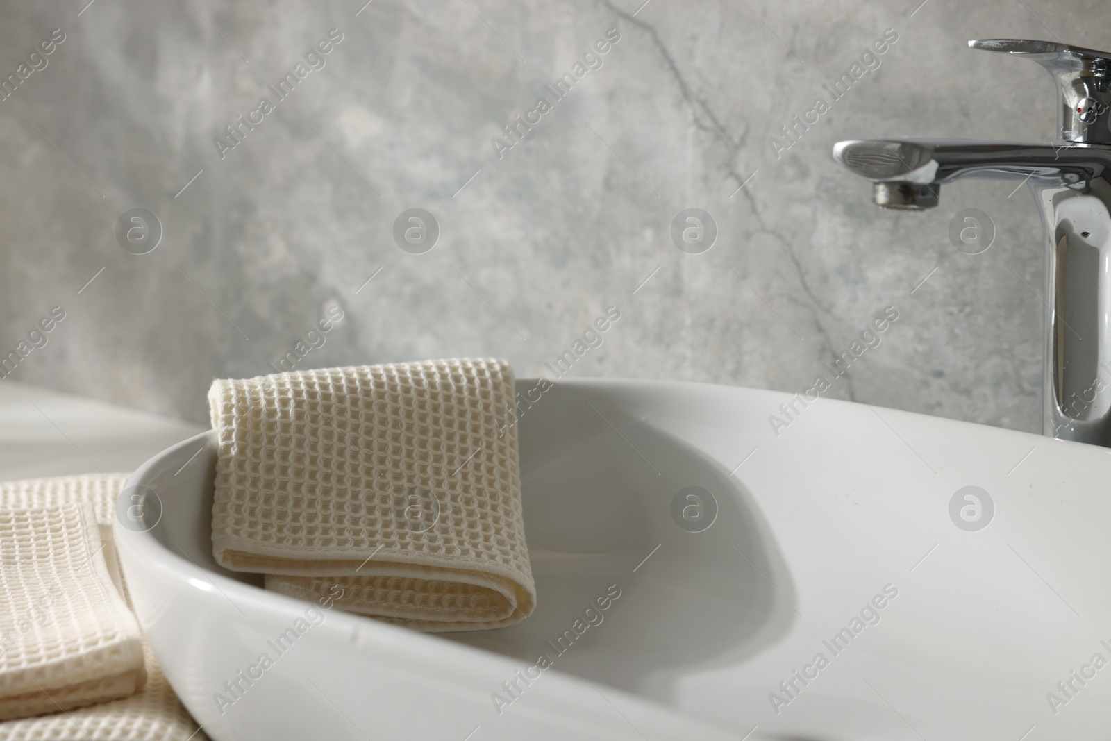 Photo of Clean waffle towels near sink in bathroom, closeup
