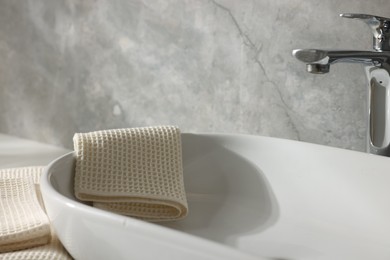 Photo of Clean waffle towels near sink in bathroom, closeup