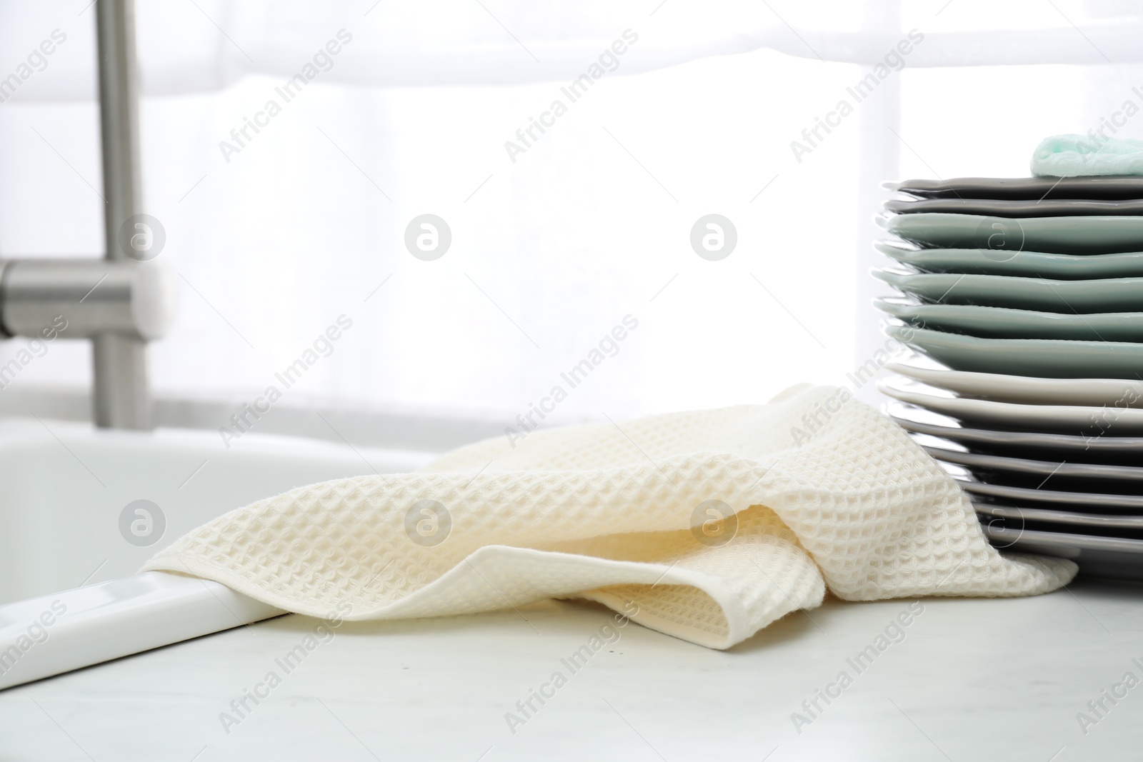 Photo of Clean waffle towel and plates on countertop near sink, closeup