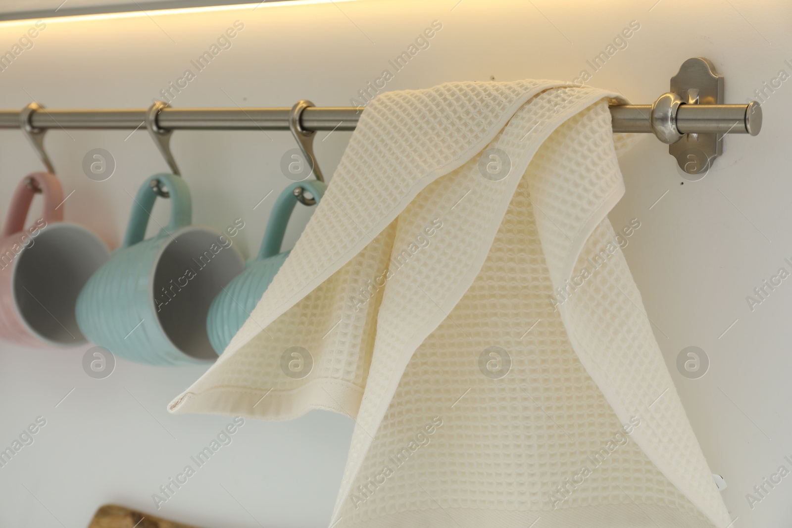 Photo of Clean waffle towel and cups hanging in kitchen, closeup