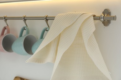 Photo of Clean waffle towel and cups hanging in kitchen, closeup