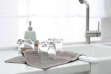 Photo of Clean glasses drying on waffle towel in kitchen, closeup