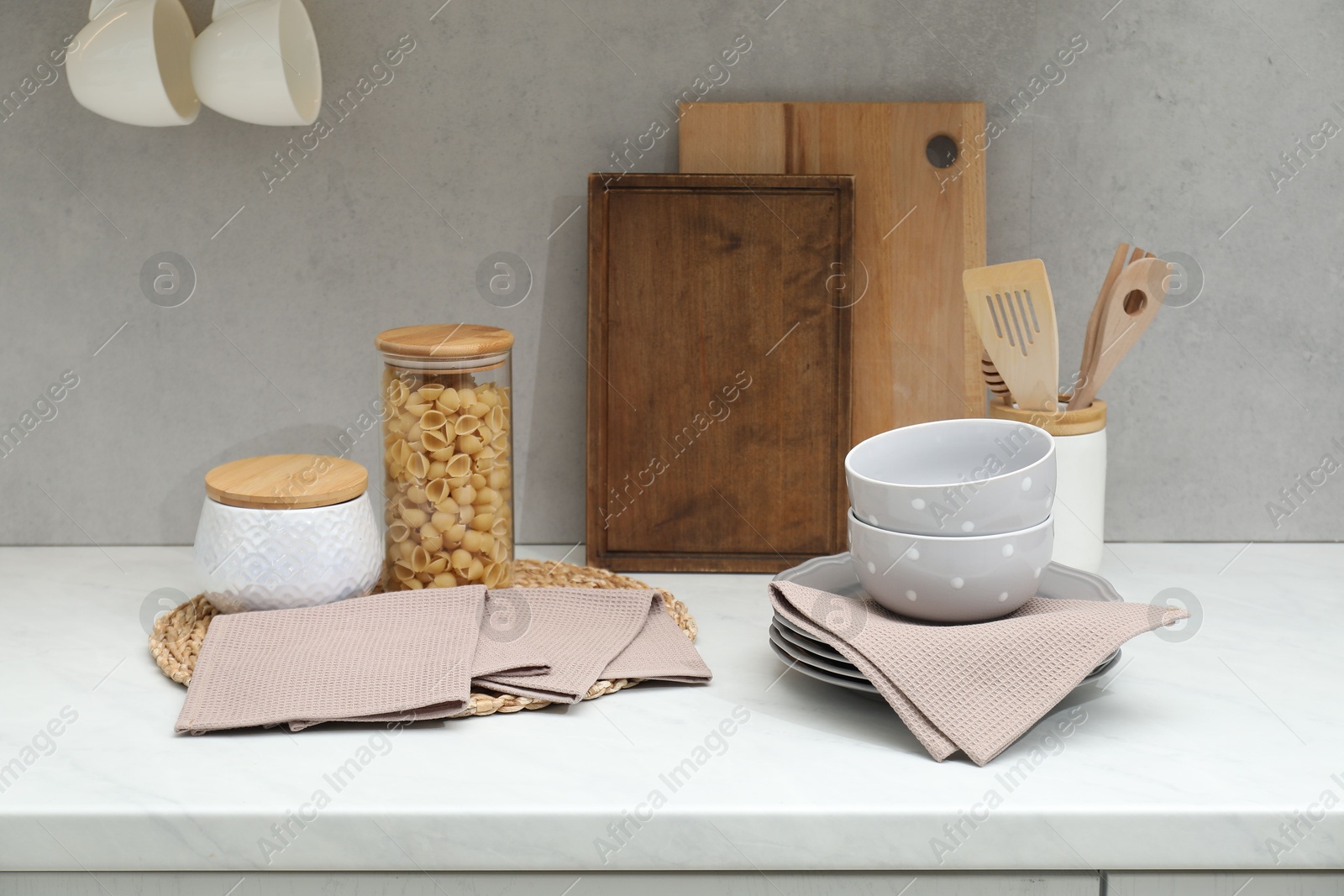 Photo of Clean dishware, waffle towels and raw pasta on countertop in kitchen
