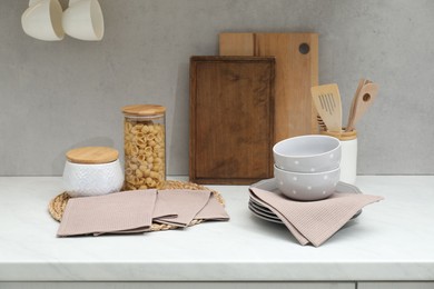 Photo of Clean dishware, waffle towels and raw pasta on countertop in kitchen