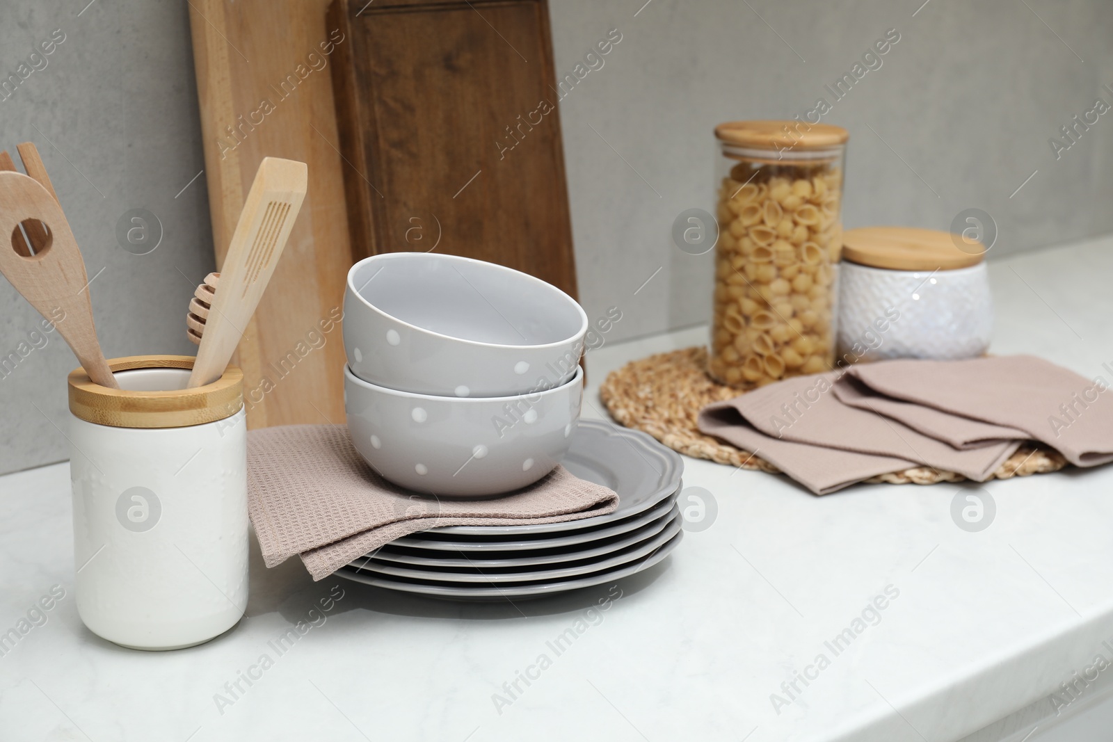 Photo of Clean dishware, waffle towels and raw pasta on countertop in kitchen