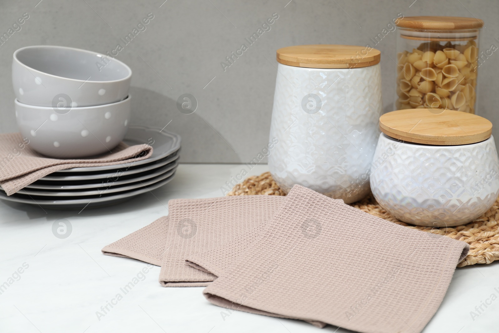 Photo of Clean dishware, waffle towels and raw pasta on countertop in kitchen, closeup