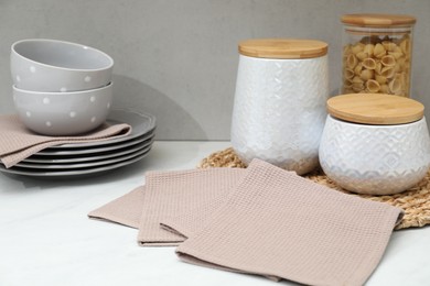 Photo of Clean dishware, waffle towels and raw pasta on countertop in kitchen, closeup