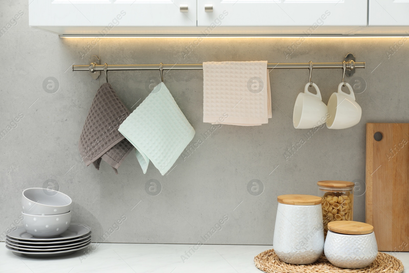 Photo of Clean dishware, waffle towels and raw pasta in kitchen