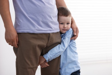 Photo of Little boy clinging to his father indoors. Separation anxiety