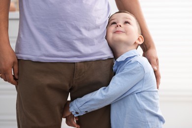 Photo of Little boy clinging to his father indoors. Separation anxiety
