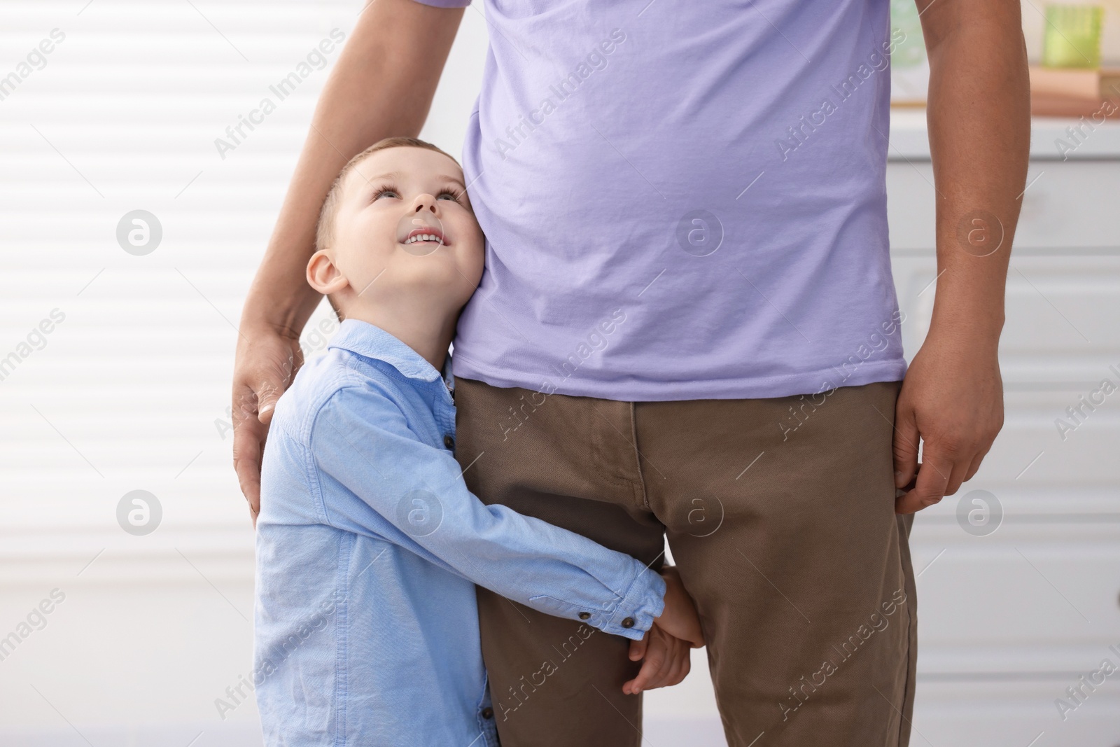 Photo of Little boy clinging to his father indoors. Separation anxiety