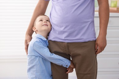 Photo of Little boy clinging to his father indoors. Separation anxiety