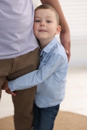 Photo of Little boy clinging to his father indoors. Separation anxiety