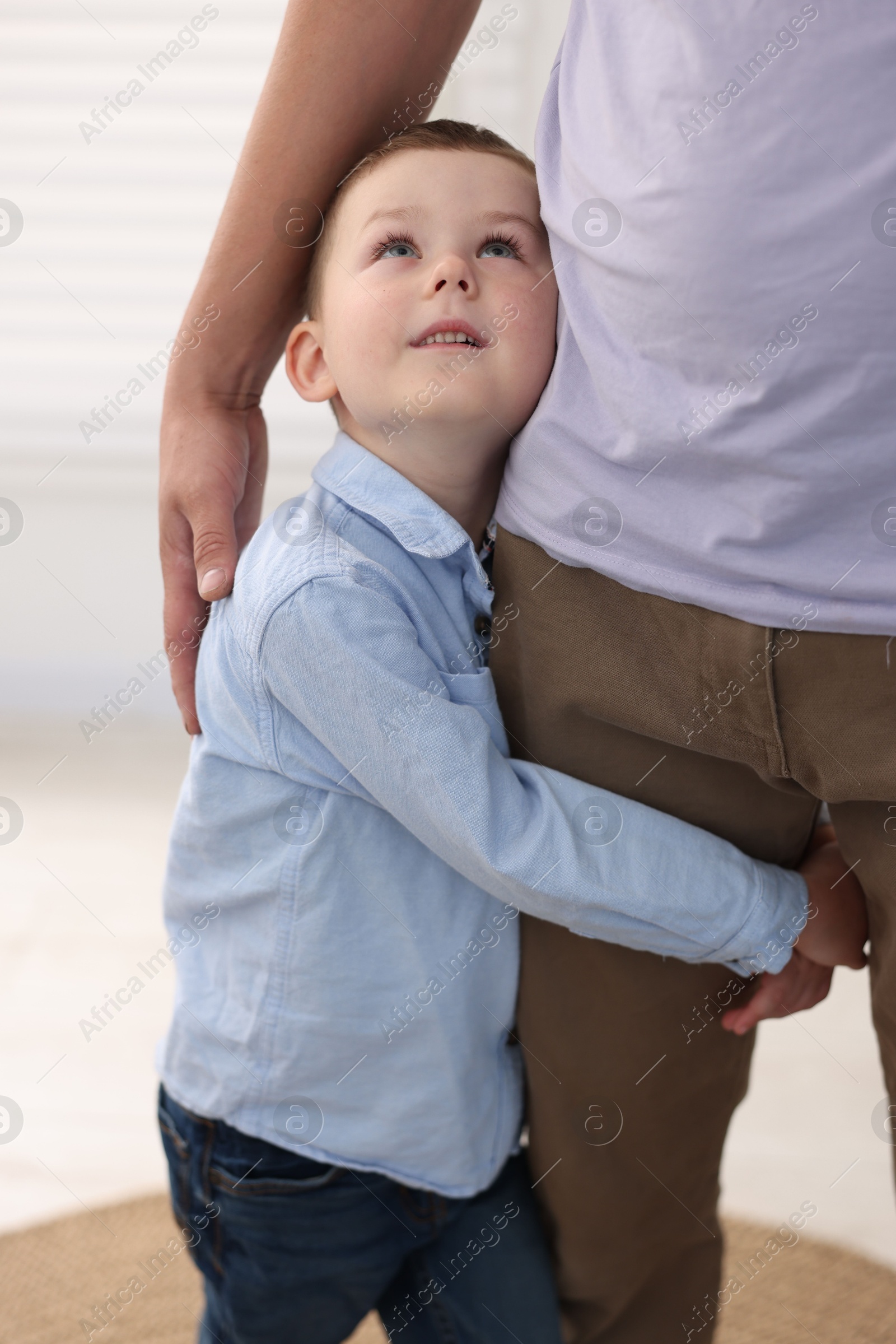 Photo of Little boy clinging to his father indoors. Separation anxiety