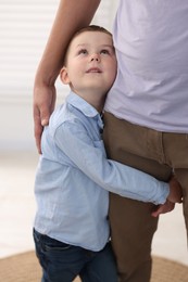 Photo of Little boy clinging to his father indoors. Separation anxiety