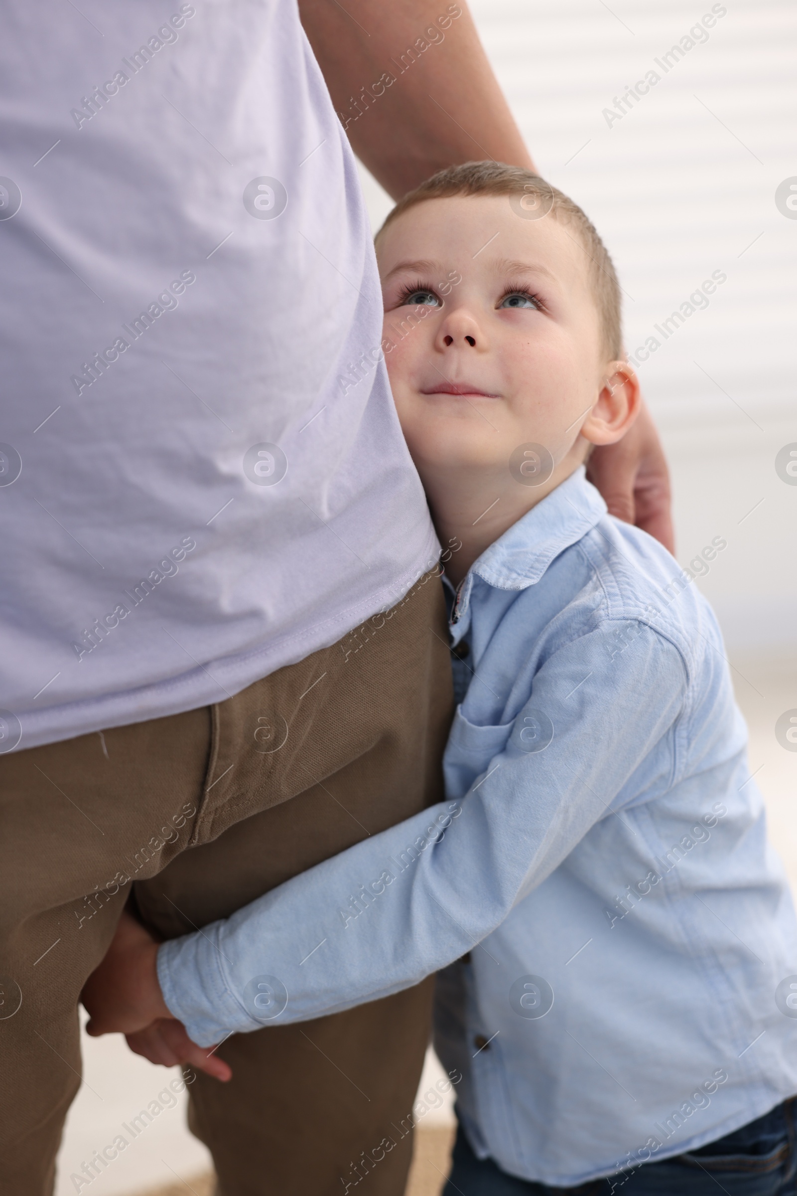 Photo of Little boy clinging to his father indoors. Separation anxiety