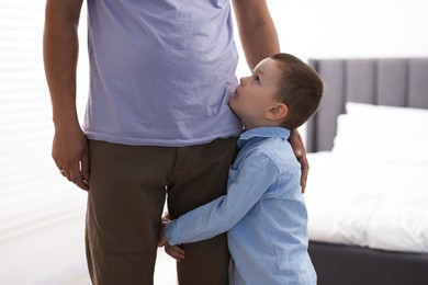 Photo of Little boy clinging to his father indoors. Separation anxiety