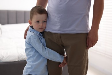 Photo of Little boy clinging to his father indoors. Separation anxiety