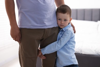 Photo of Little boy clinging to his father indoors. Separation anxiety