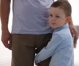Photo of Little boy clinging to his father indoors. Separation anxiety