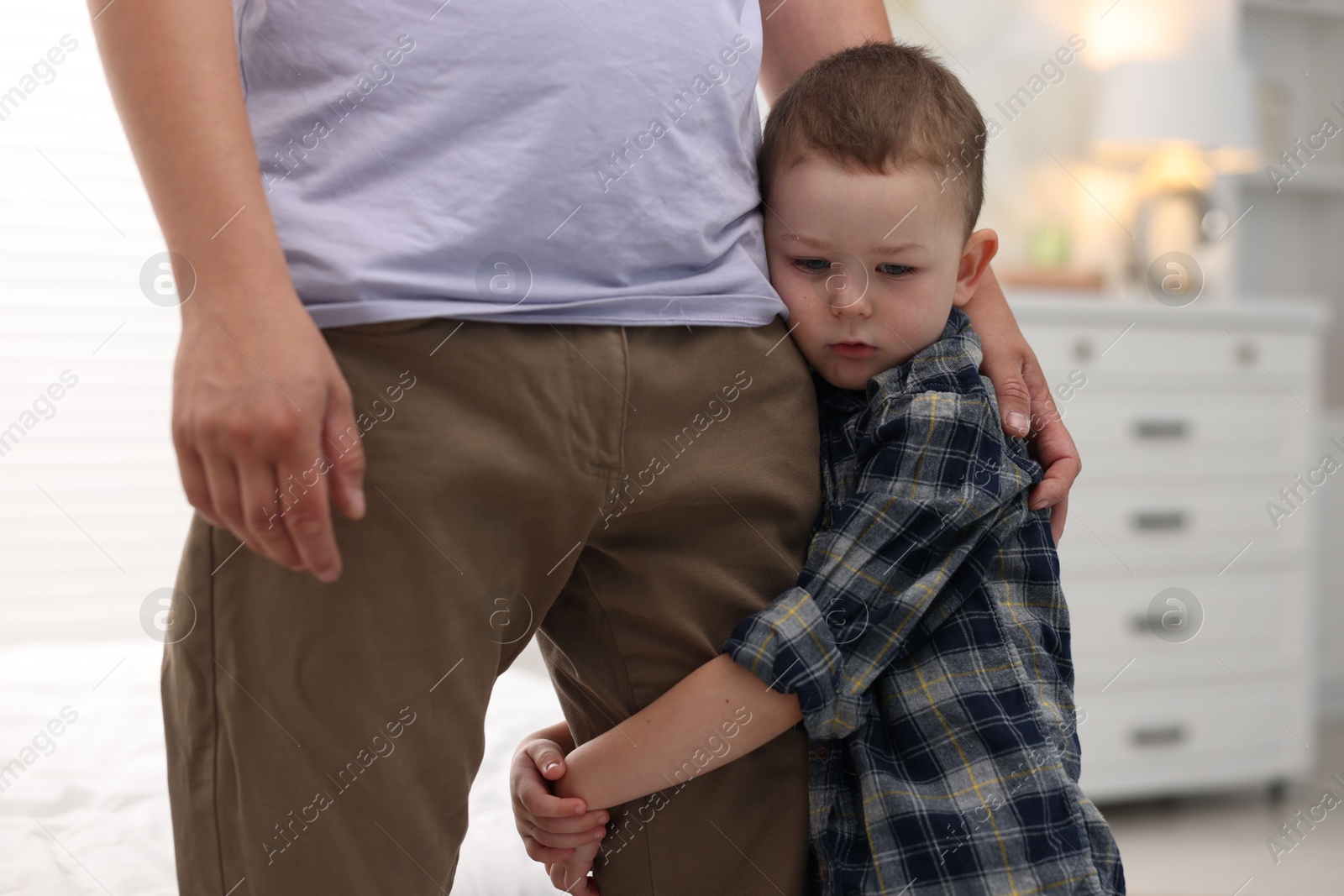 Photo of Little boy clinging to his father indoors. Separation anxiety