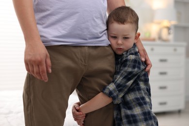 Photo of Little boy clinging to his father indoors. Separation anxiety