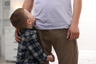 Photo of Little boy clinging to his father indoors. Separation anxiety
