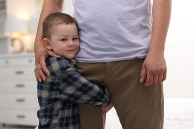 Photo of Little boy clinging to his father indoors. Separation anxiety