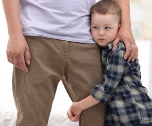 Photo of Little boy clinging to his father indoors. Separation anxiety