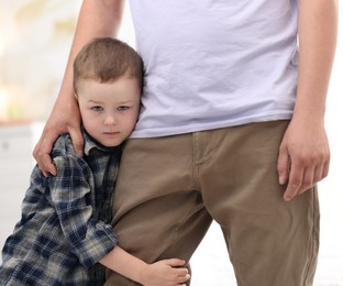 Photo of Little boy clinging to his father indoors. Separation anxiety