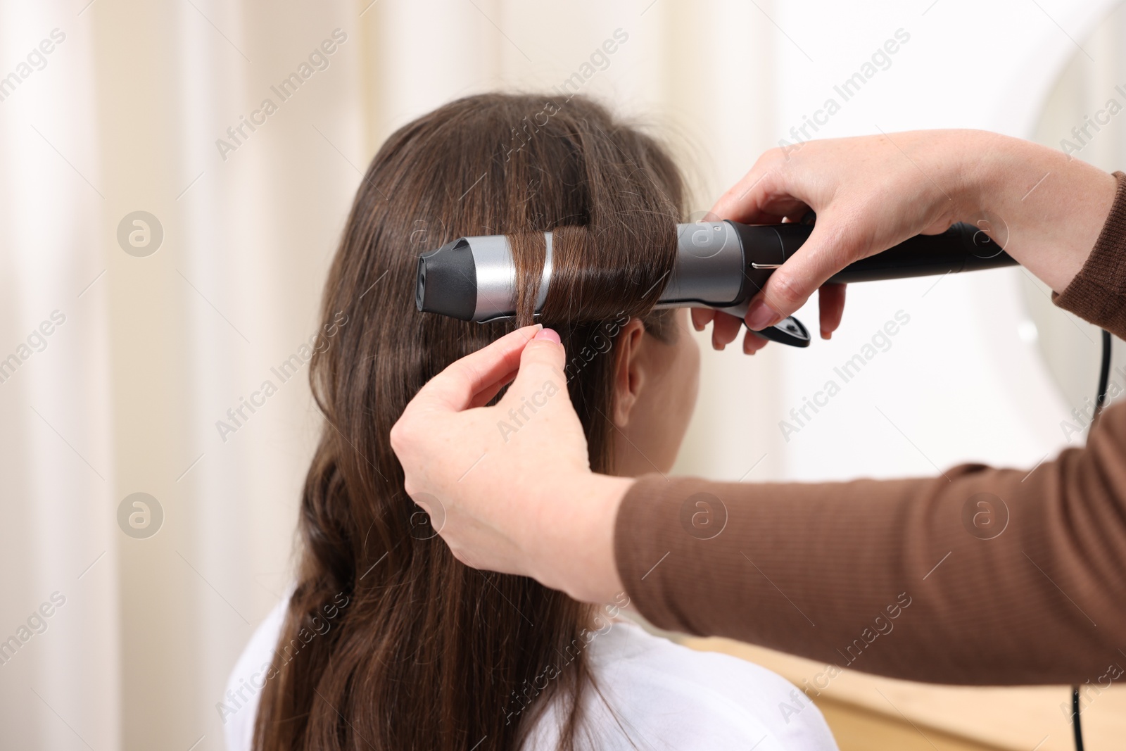 Hairdresser curling woman's hair in salon, closeup Photo of Hairdresser curling woman's hair in salon, closeup