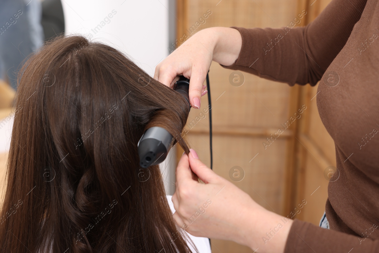 Hairdresser curling woman's hair in salon, closeup Photo of Hairdresser curling woman's hair in salon, closeup