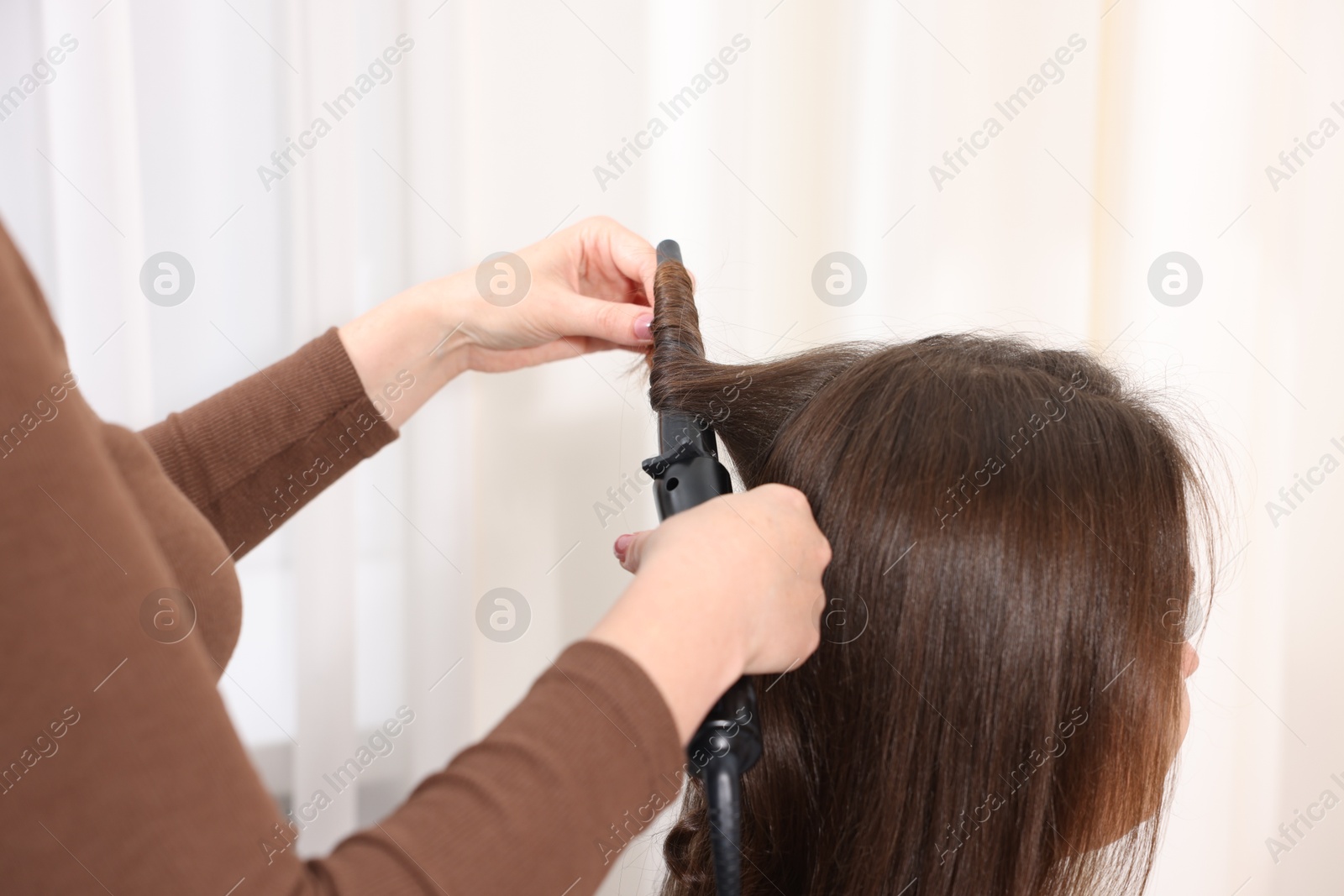 Hairdresser curling woman's hair in salon, closeup Photo of Hairdresser curling woman's hair in salon, closeup