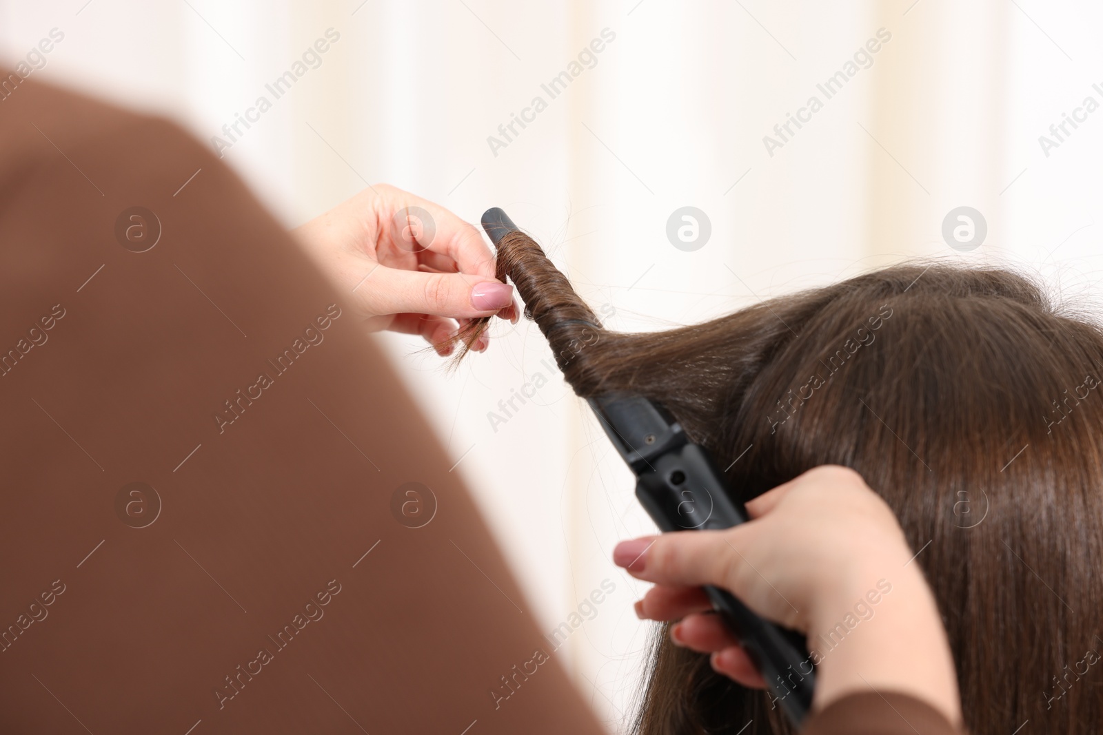 Hairdresser curling woman's hair in salon, closeup Photo of Hairdresser curling woman's hair in salon, closeup