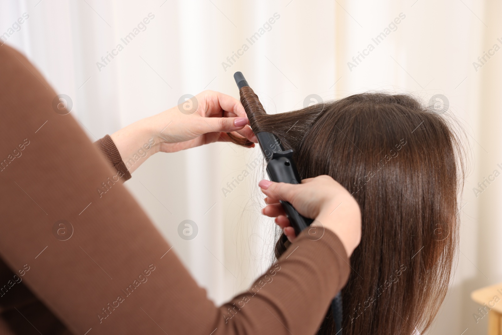 Hairdresser curling woman's hair in salon, closeup Photo of Hairdresser curling woman's hair in salon, closeup