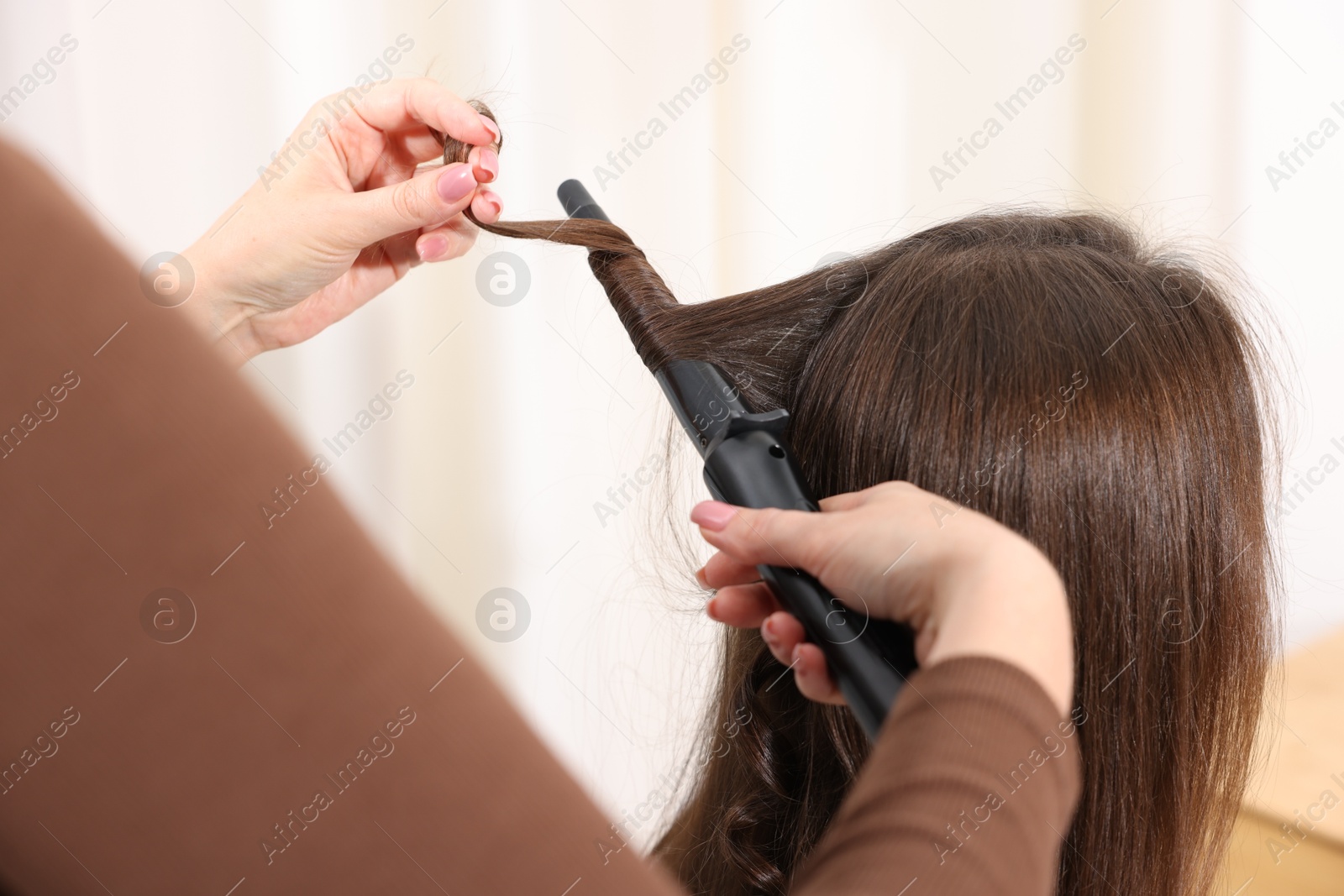 Hairdresser curling woman's hair in salon, closeup Photo of Hairdresser curling woman's hair in salon, closeup