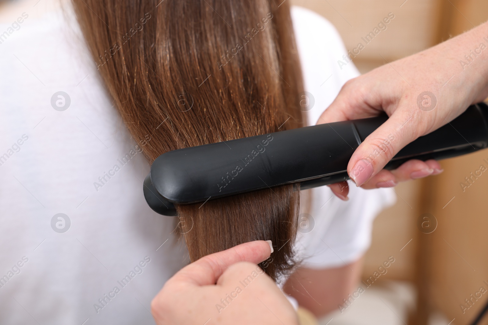 Hairdresser straightening woman's hair with flat iron in salon, closeup Photo of Hairdresser straightening woman's hair with flat iron in salon, closeup