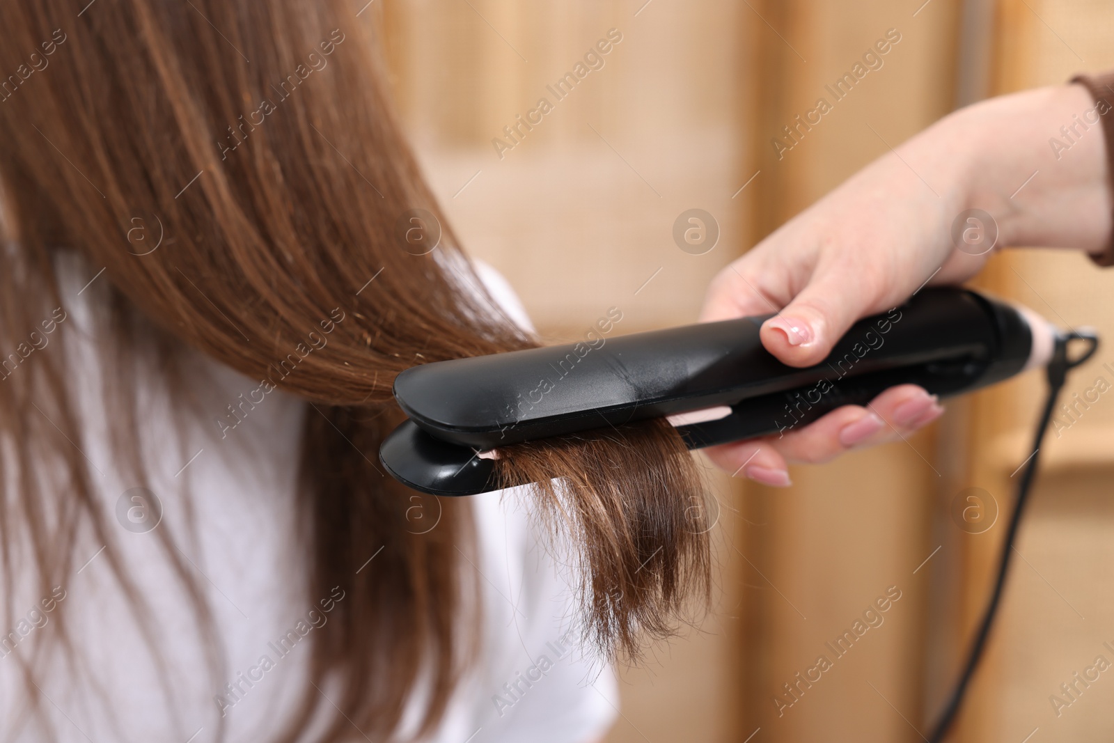 Hairdresser straightening woman's hair with flat iron in salon, closeup Photo of Hairdresser straightening woman's hair with flat iron in salon, closeup