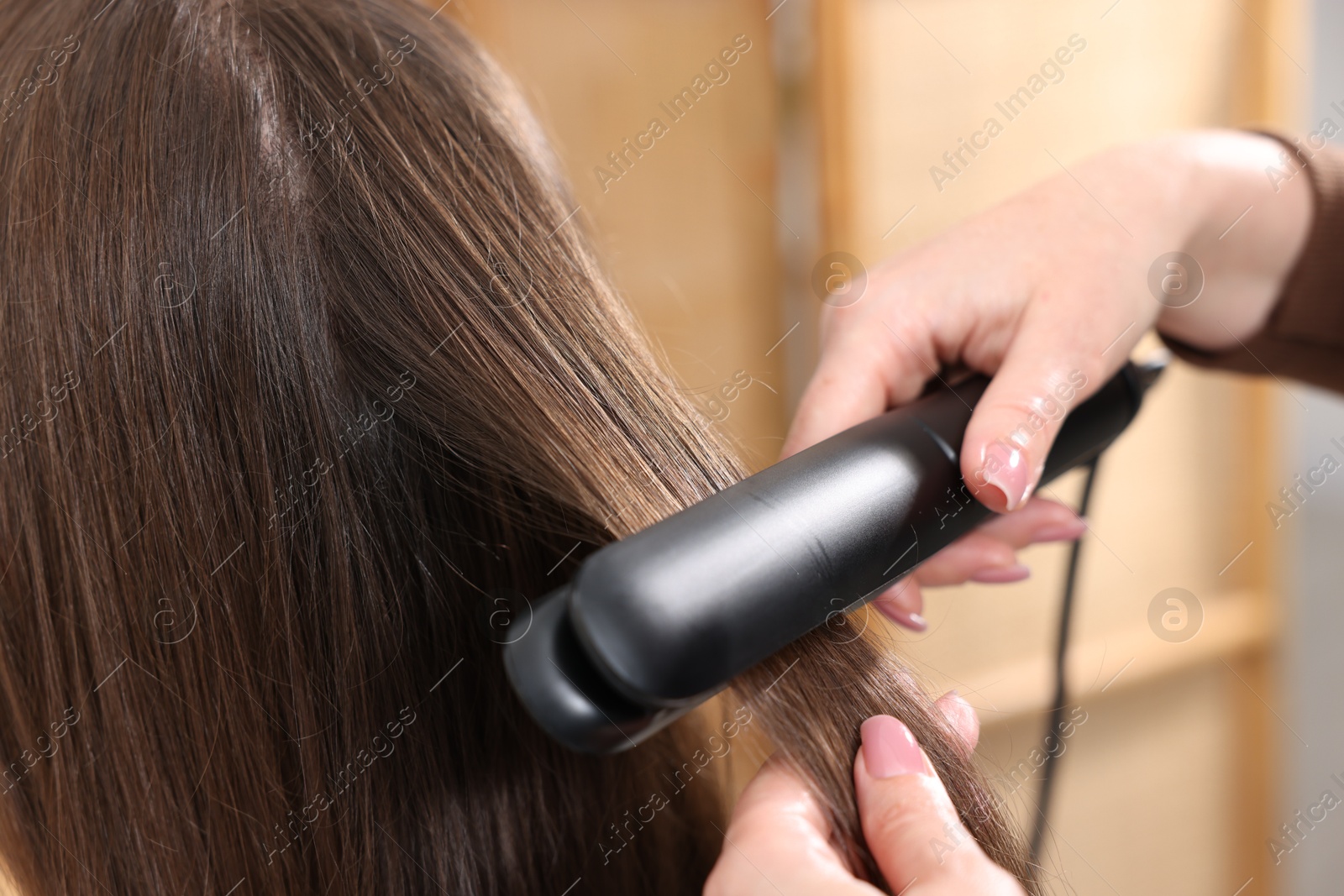 Hairdresser straightening woman's hair with flat iron in salon, closeup Photo of Hairdresser straightening woman's hair with flat iron in salon, closeup