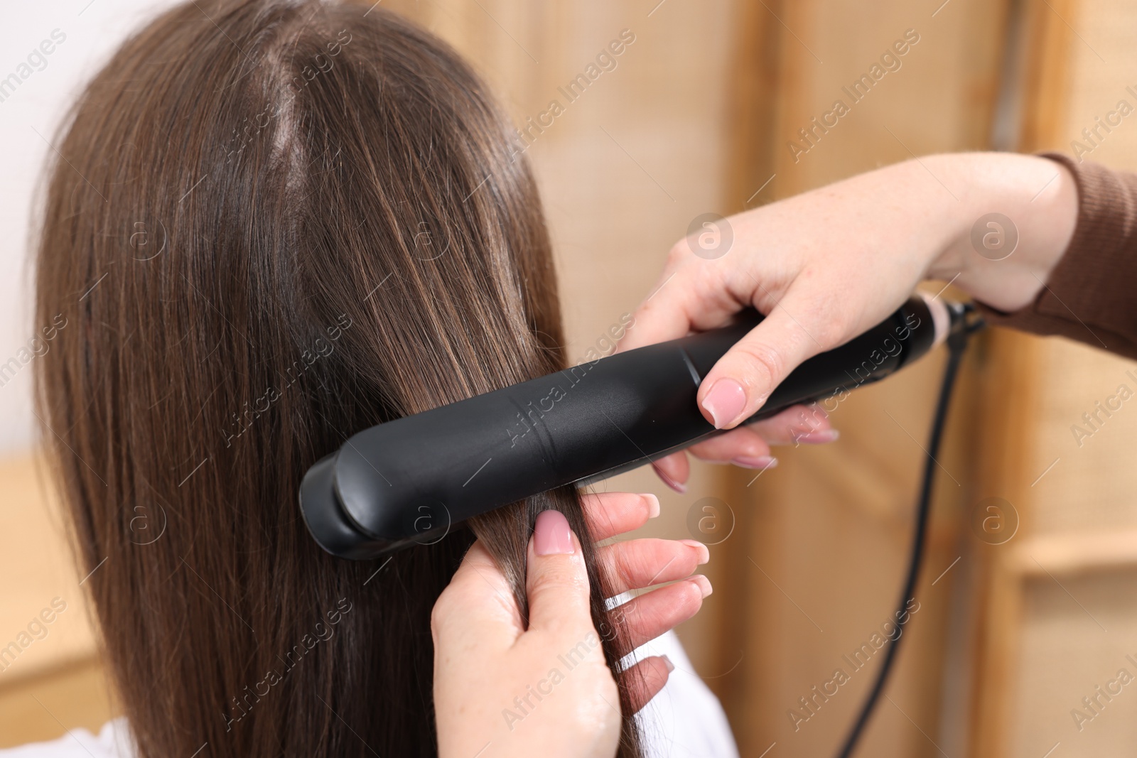 Hairdresser straightening woman's hair with flat iron in salon, closeup Photo of Hairdresser straightening woman's hair with flat iron in salon, closeup
