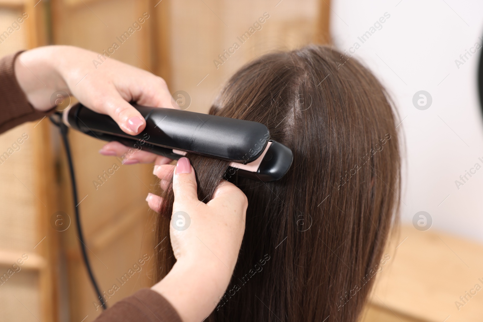 Hairdresser straightening woman's hair with flat iron in salon, closeup Photo of Hairdresser straightening woman's hair with flat iron in salon, closeup