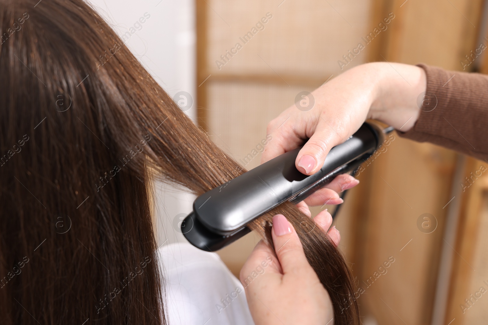 Hairdresser straightening woman's hair with flat iron in salon, closeup Photo of Hairdresser straightening woman's hair with flat iron in salon, closeup