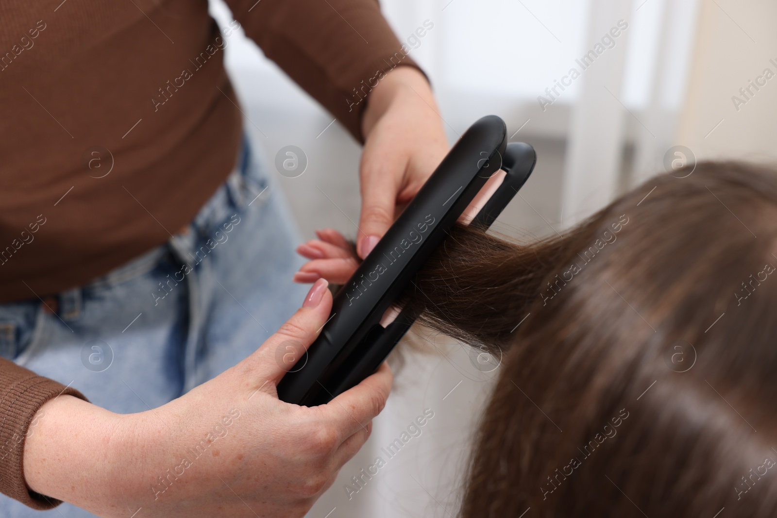 Hairdresser straightening woman's hair with flat iron in salon, closeup Photo of Hairdresser straightening woman's hair with flat iron in salon, closeup