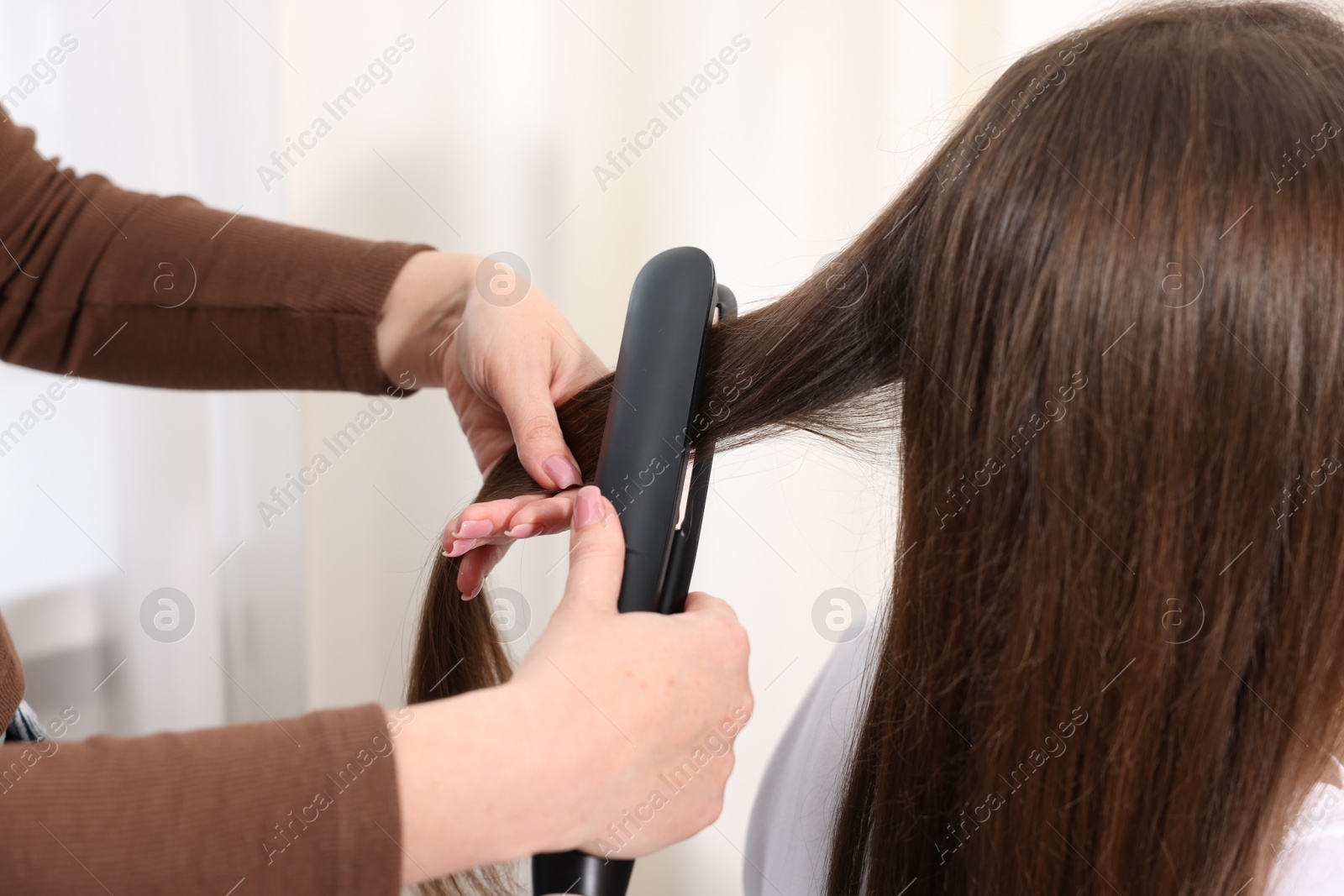 Hairdresser straightening woman's hair with flat iron in salon, closeup Photo of Hairdresser straightening woman's hair with flat iron in salon, closeup
