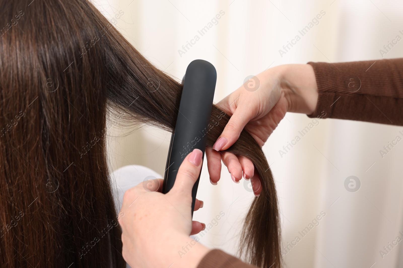 Hairdresser straightening woman's hair with flat iron in salon, closeup Photo of Hairdresser straightening woman's hair with flat iron in salon, closeup