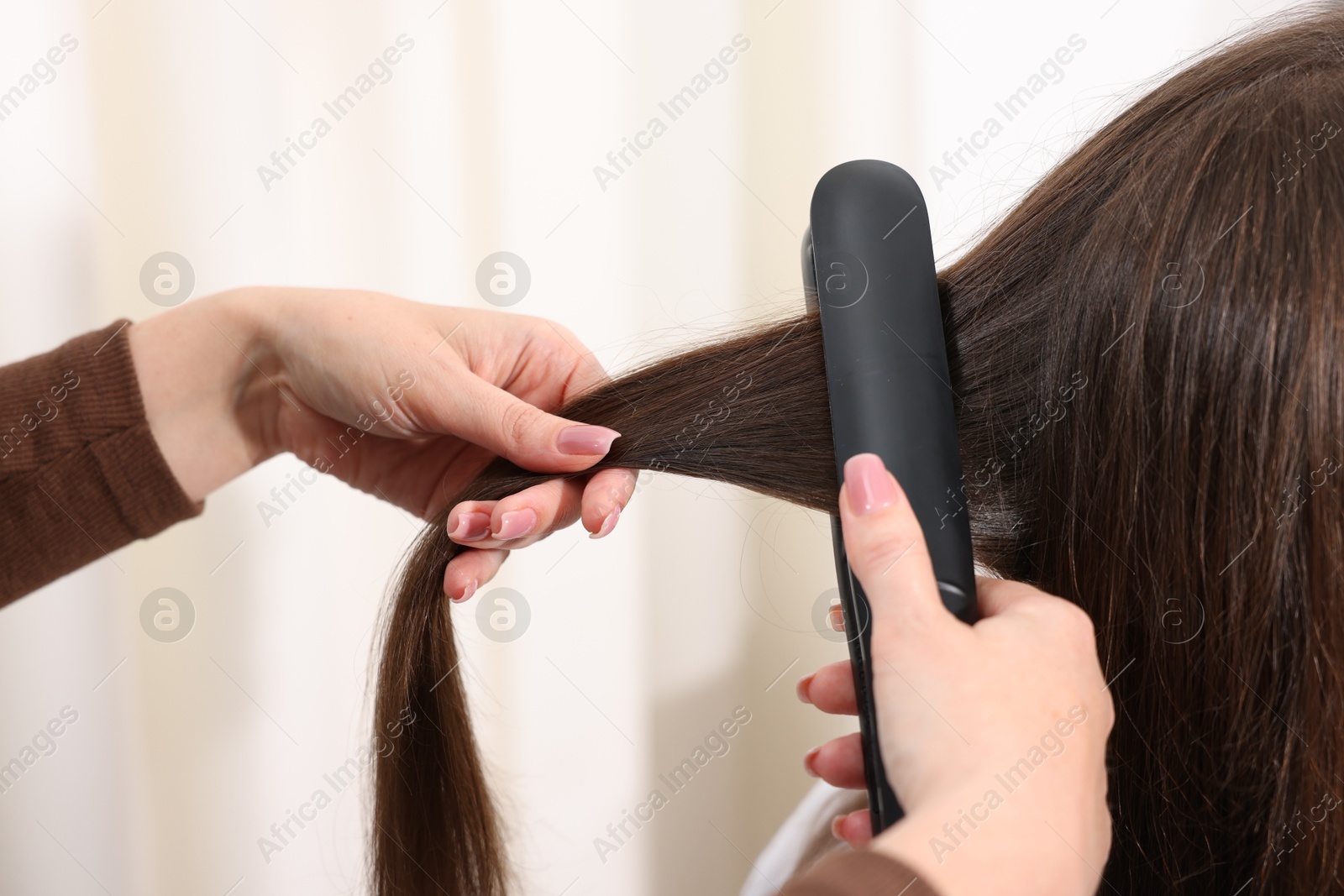 Hairdresser straightening woman's hair with flat iron in salon, closeup Photo of Hairdresser straightening woman's hair with flat iron in salon, closeup