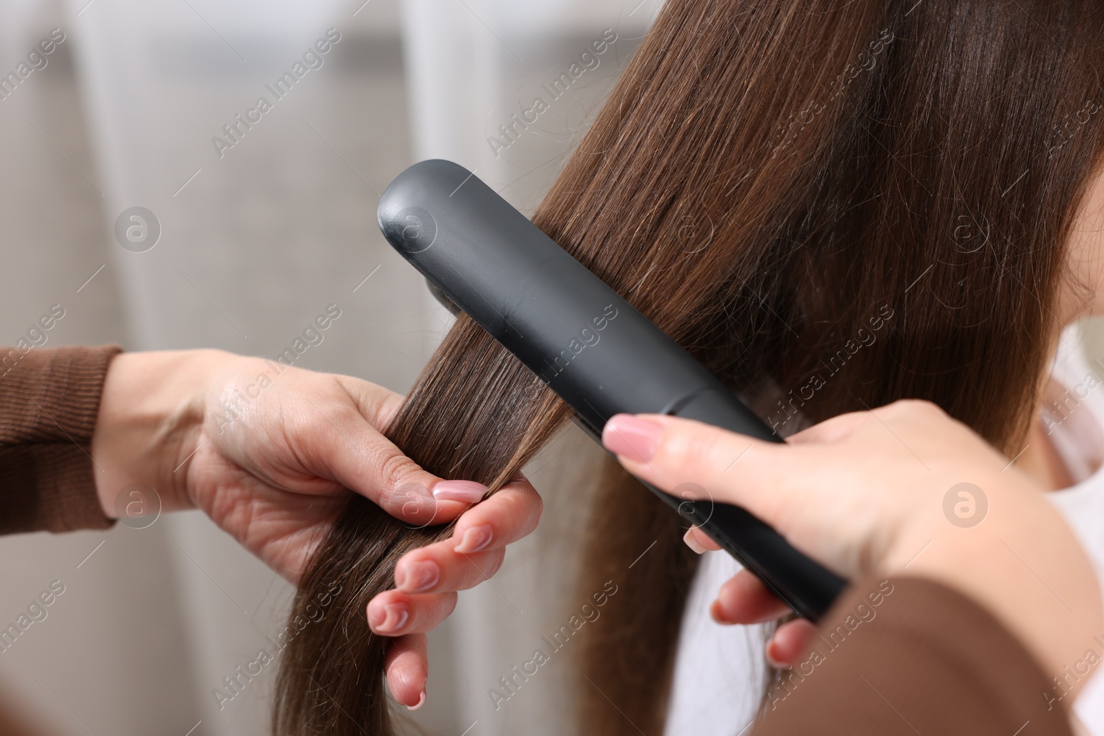 Hairdresser straightening woman's hair with flat iron in salon, closeup Photo of Hairdresser straightening woman's hair with flat iron in salon, closeup